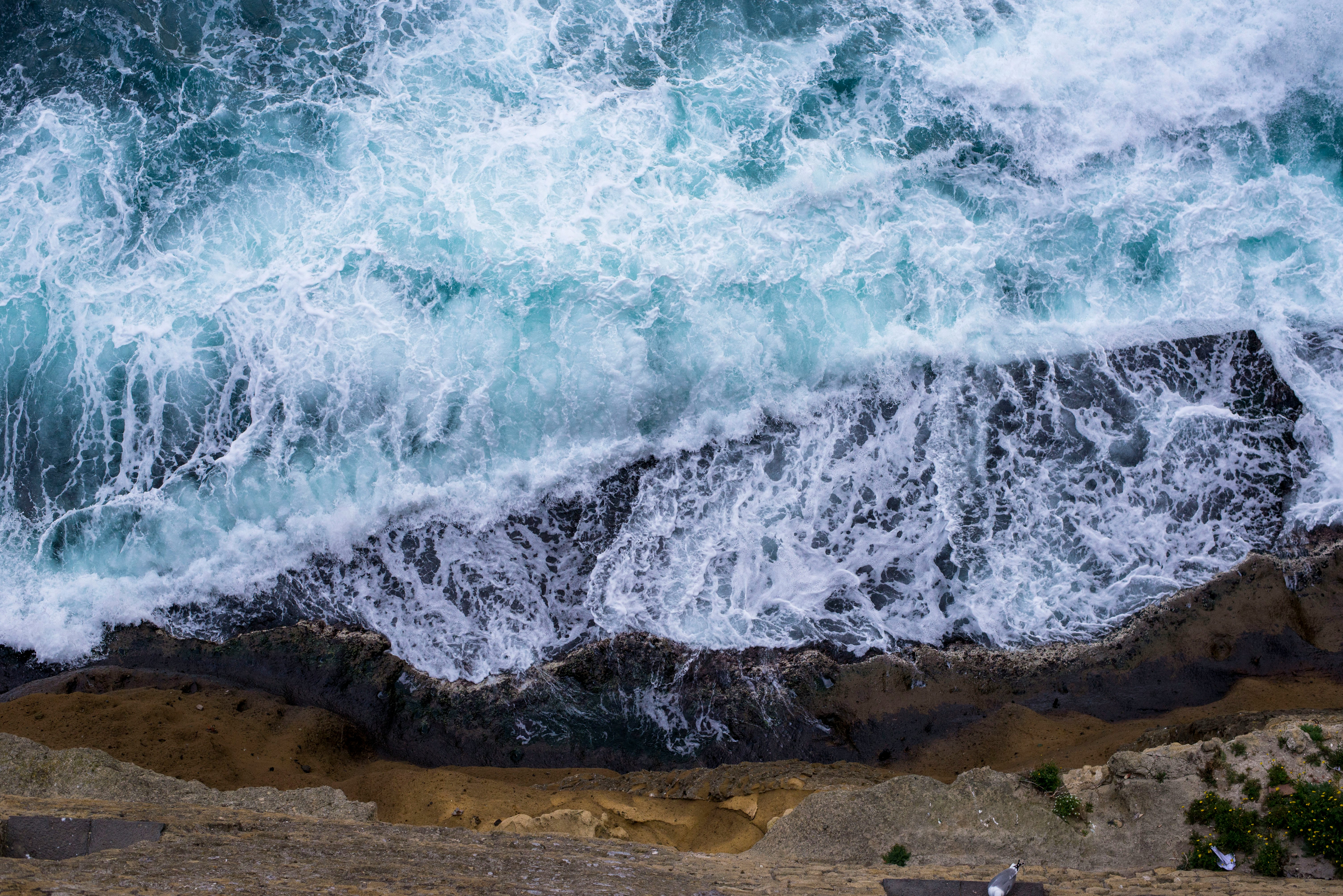 aerial view of waves crushing against rocks